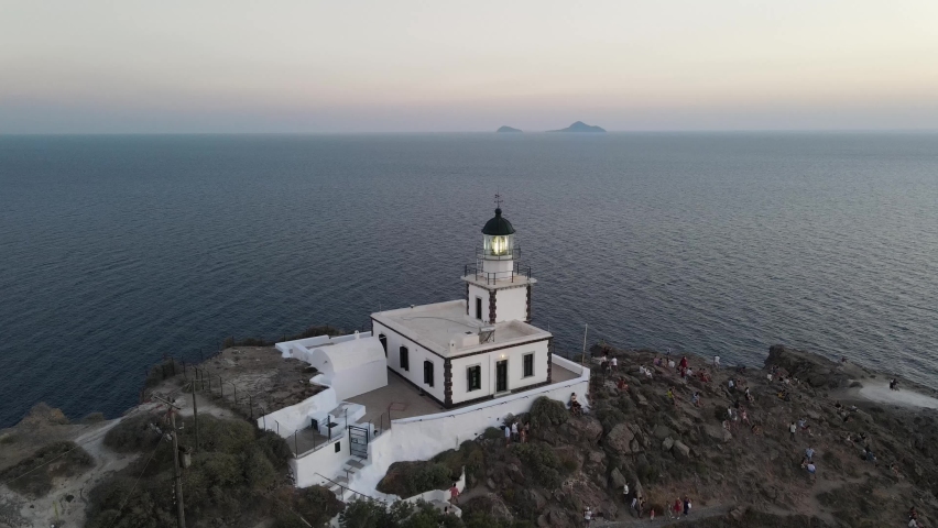 Aerial view of the famous Akrotiri lighthouse on top of rocky mountain during a beatiful sunset in Santorini, Greece