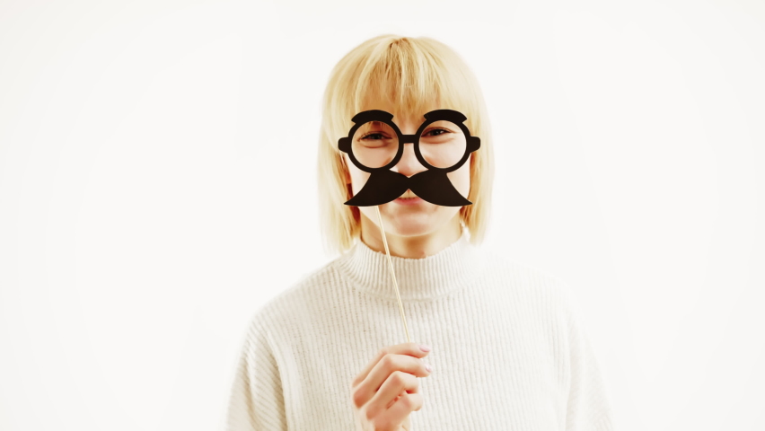 Goofy Woman Caucasian Blonde Holding Mustache And Glasses On A Stick On her face, thinking to herself