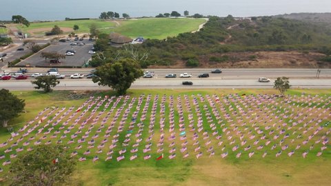 Aerial Of Waves Of Flags On The Green Lawn At Alumni Park At Pepperdine University In Malibu - drone pullback