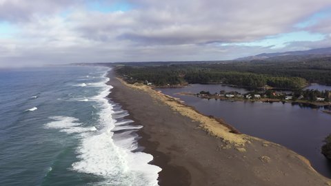 Garrison lake in Port Orford at the Southern Oregon Coast, divided from the ocean by a thin strip of beach, drone shot 4k.