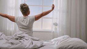 Woman wakes up in morning in good mood after healthy sleep. Middle-aged women sleeping sweetly, waking up, lazily stretching on bed at home, sunlight through window. Concept of beginning of new day. - Powered by Shutterstock - Get 15% off with code: PIKWIZARD15
