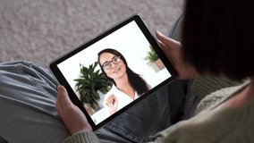 Female patient talking doctor on tablet by video calling, distance consulting with psychotherapist in white coat . Telemedicine, remote healthcare services concept. Over shoulder view 4k