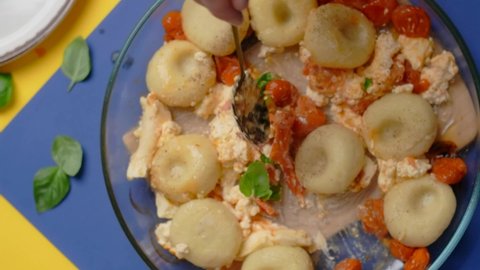Vertical tabletop video: chef takes cooked potato dumpling with tomatoes and feta cheese by spoon