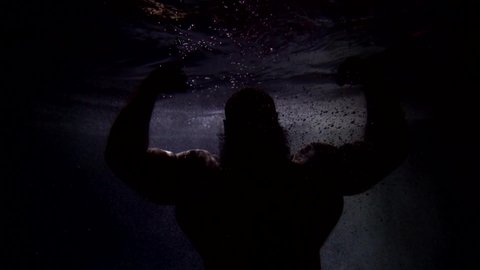 dark silhouette of Poseidon in depth of ocean, brawny man with muscular hands and torso underwater