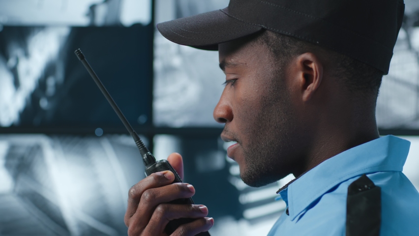 Close up of security guard look at monitor and report on walkie talkie. Security office  Royalty-Free Stock Footage #1089328935