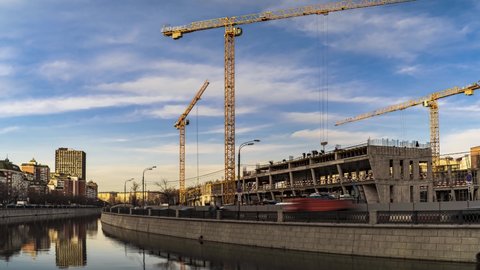 Energetic work of cranes and construction workers during the construction of the office and academic building of the university on the river embankment, time lapse
