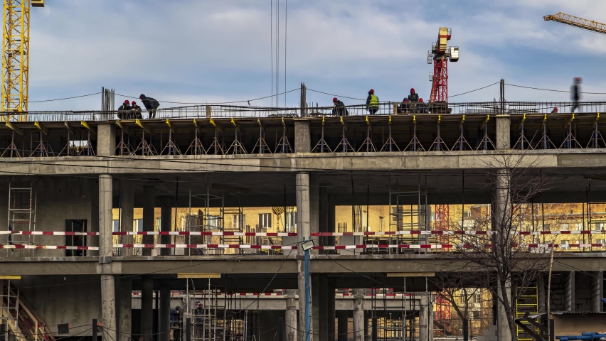 Energetic work of cranes and construction workers during the construction of the office and academic building of the university on the river embankment, time lapse