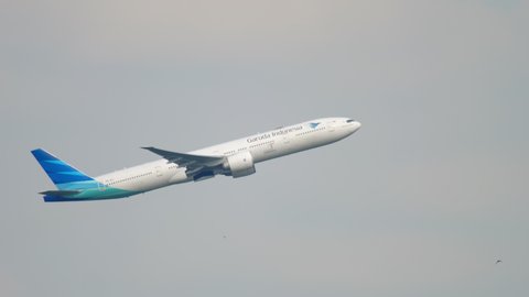AMSTERDAM, THE NETHERLANDS - JULY 26, 2017: Side view Boeing 777 of Garuda Indonesia take off, climb at Schiphol Airport, Amsterdam. Garuda Indonesia is the national airline of Indonesia