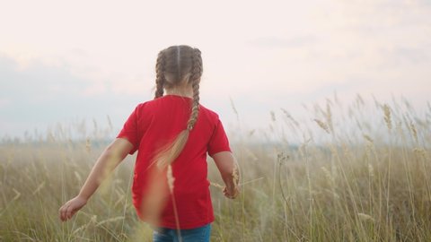 little girl running across the field in nature in the park. happy family kid dream concept. little girl running in dry grass in wild park. free girl fun happy childhood and family concept