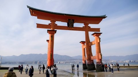 Miyajima, Japan - Apr 23, 22: People walking in front of the great Torii of Miyajima also know as the floating Torii during summer. High quality footage.