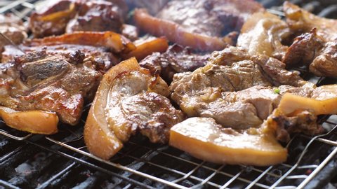 Barbecue in the backyard. Sliced pieces of meat are cooked on the grate. The pieces look very appetizing. Cutlery checks the readiness of cooking chopped pieces of meat. Delicious fried pork.