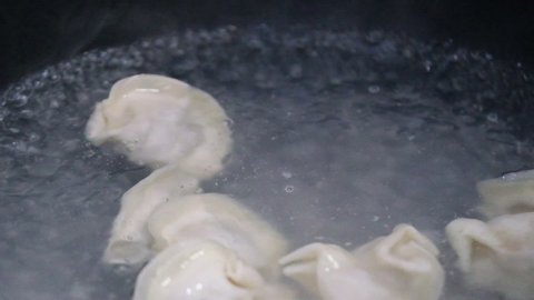 super slow motion. Close up hand putting raw dumpling into boiling water. Cooking traditional Chinese food during Spring Festival