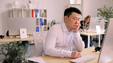Portrait of attractive rested sleepy asian office worker which awaiking from sleep in office and continue to work.