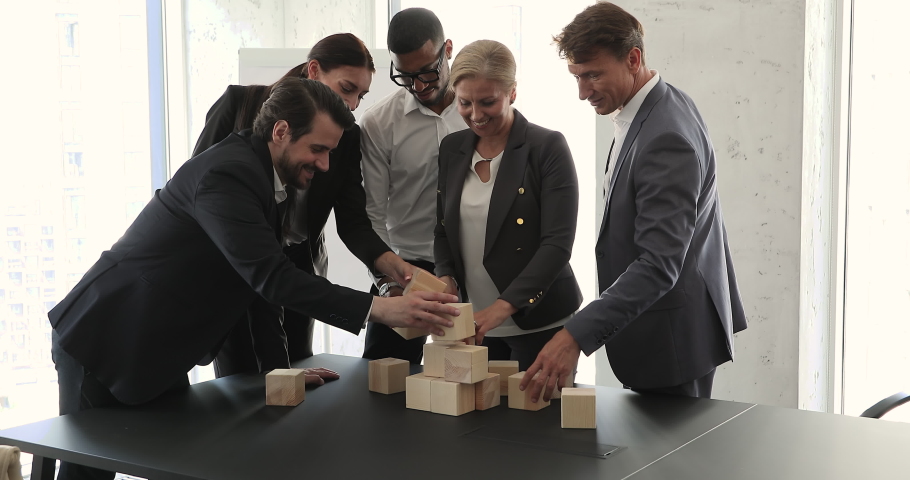 Senior adult woman coach business trainer psychologist provide teambuilding game activity in multiethnic staff group. Motivated diverse mixed race team businesspeople colleagues build tower from cubes Royalty-Free Stock Footage #1089340181