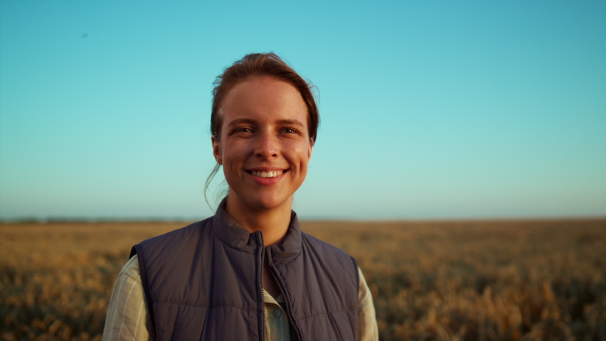 Portrait happy farmer posing endless farmland field. Agricultural industry work. Smiling woman delighted professional agronomist inspecting harvest in golden sunlight. Beautiful rural landscape view. Royalty-Free Stock Footage #1089340439