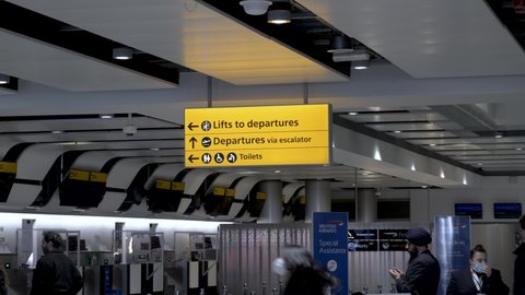 London , United Kingdom (UK) - 03 19 2022: Yellow directional signage at Heathrow International Airport Terminal 3, passengers passing by going about their business making their way to the departure’s