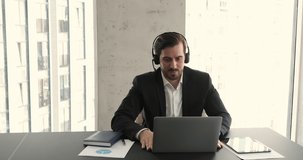Friendly smiling businessman professional coach wear wireless headset lead virtual workshop webinar using laptop. Young adult manager expert join web briefing in conference app give video consultation