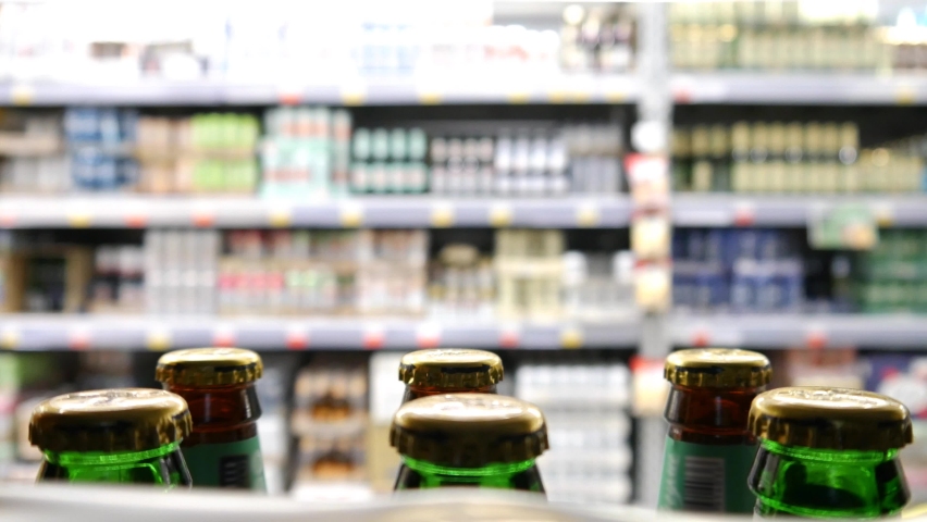 Close-up of beautiful bottles of beer on a store shelf and a man takes a few Royalty-Free Stock Footage #1089344385