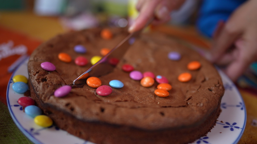 Hand slicing chocolate birthday cake closeup person cuting cake