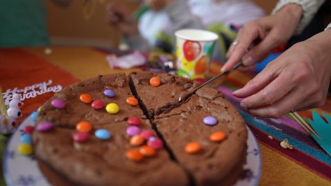 Hand slicing chocolate birthday cake closeup person cuting cake