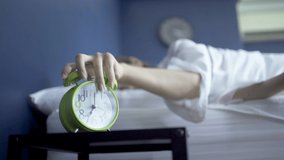 Alarm clock opposite of sleepy young woman stretching hand to ringing alarm willing turn it off. woken by signal, not getting enough sleep concept. - Powered by Shutterstock - Get 15% off with code: PIKWIZARD15