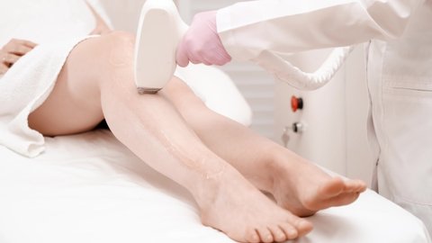Flash of diode laser hair removal, Beautician removes hair on beautiful female legs, Hair removal for smooth skin, laser procedure at beauty studio or clinic, Body care epilation treatment.