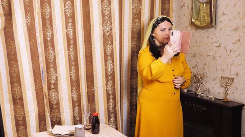 A Jewish woman in a wig and veil takes a selfie on the eve of Pesach. Overall plan