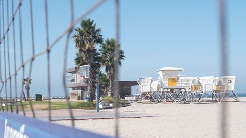 Volley ball net on court for volleyball game on beach, California coast, USA. Sport field or playground for players on sandy ocean shore, lifeguard station and palm trees on Mission beach, San Diego.