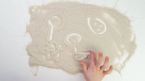 child paint finger on sand. kids Game. Top view draw on the sand. Caucasian hands write text in beige sand. Vacation and travel. Beach on vacation. Sand painting. Creativity from natural materials.
