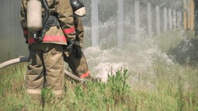 Firefighters. Clip. Two masked men who conduct exercises with a hose and water with special equipment and in a special uniform.