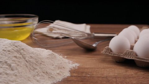 Slow motion of falling eggs into flour. Egg yolks dropping into flour, slow motion, camera slide following action. Yolk Falls Into the Flour. Preparation of the dough.