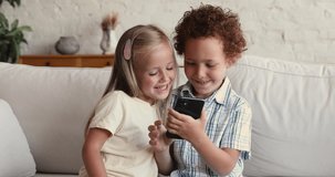 Generation addicted to gadgets. Cute little kids elder brother younger sister play web game on cell without parents. Small boy girl siblings use safe secure internet on phone with parental control app