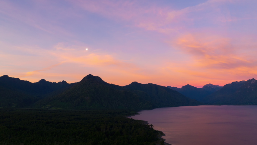 Time lapse Of Beautiful Purple Pink Sunset Dramatic Clouds Over Silhouette Of Coastline At Lake Chapo. Locked Off