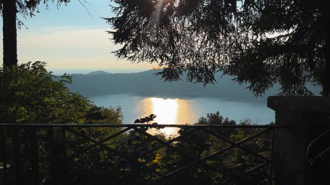 Pov shot from balcony of beautiful Lago di Nemi in Italy during sun reflecting on water surface - Rome,Italy