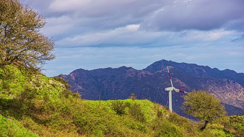 Static view of a white wind turbine in Messina, Taormina, Italy at daytime in timelapse. Windmill park, huge windmill generator turbines over the hilly terrain, green technology.