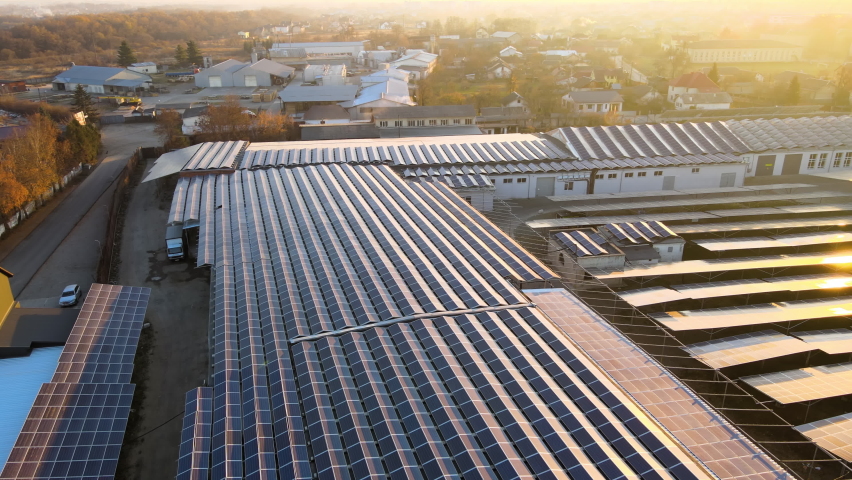 Aerial view of blue photovoltaic solar panels mounted on industrial building roof for producing green ecological electricity. Production of sustainable energy concept