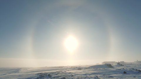 Halo effect in the clear sky against a snow-covered landscape in the Arctic