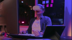 metaverse meeting technology,creative asian adult male engineer programing wearing vr headset gear working with virtual augmented reality 3d model in home studio at night