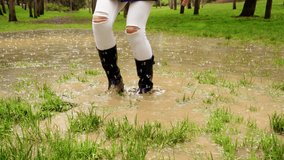 Close-up of unrecognizable woman jumping with galoshes on pond. Horizontal low angle view of wellingtons on rainy pound splashing with mud. Nature and people backgrounds. - Powered by Shutterstock - Get 15% off with code: PIKWIZARD15