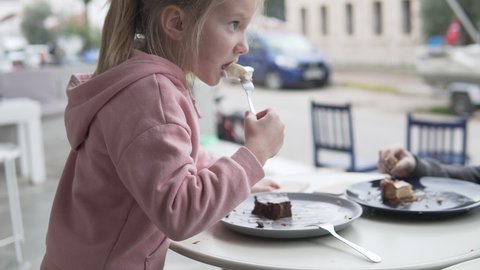 A cute little girl eats a piece of chocolate cake in a cafe in Turkey.