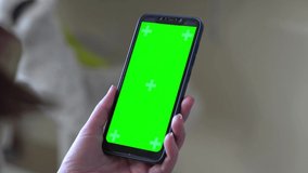 Young woman at modern room using smartphone mobile phone with green white screen chroma key with track points watching content videos blogs Close up. Girl using mobile phone on Internet. Soft focus