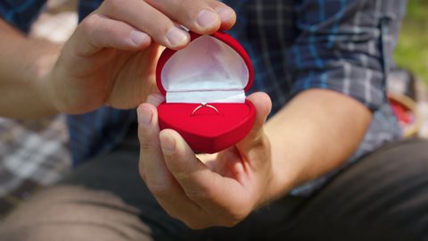 Will you merry me. Close up shot of unrecognizable caucasian man opening jewelry box with engagement diamond ring, slow motion