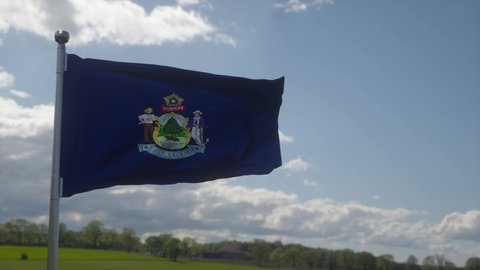 Maine flag on a flagpole waving in the wind in the sky. State of Maine in The United States of America