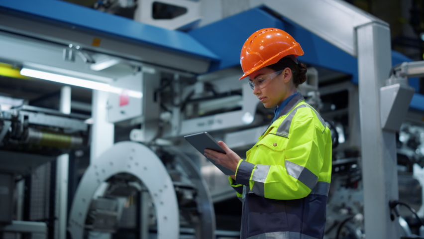 Woman supervisor looking tablet computer in huge manufacturing company. Focused industrial worker analyzing project modern plant. Safety uniform engineer check business on digital tad at factory. Royalty-Free Stock Footage #1089369617