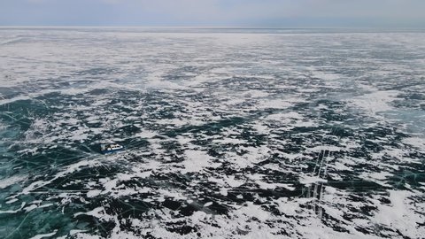 The endless lake of Baikal. A view from above of a hovercraft gliding on cracked and hummocked ice. Passenger transport in winter. A high cross-country vehicle able to reach hard-to-reach regions.