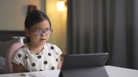 Asian child wearing blue block eyeglasses for fun learning on computer tablet or kid girl student smile to enjoy video call talking or speak and studying online class or person learn from home school
