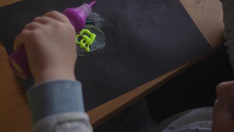 Closeup top view 4k stock video footage of cute small hand of little baby. Little child's hands dropping different bright paints on black  paper. Finger painting and drawing. Early development, art
