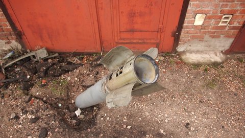 Close-up view 4k stock video footage of real unexploded military missile, torpedo or shell stuck in ground near doors of garages outdoors. Moments of dreadful war of Russia against Ukraine in 2022