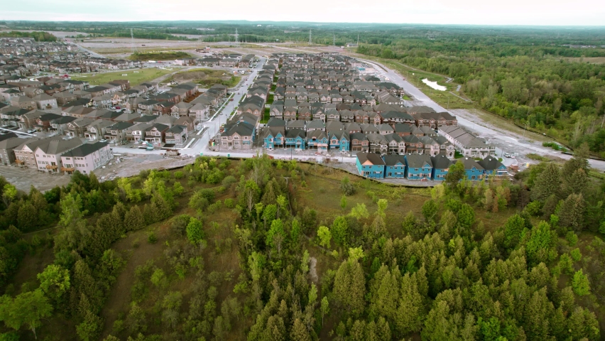 Overhead aerial view of new residential houses under construction next to forest. New neighborhood homes with siding being installed