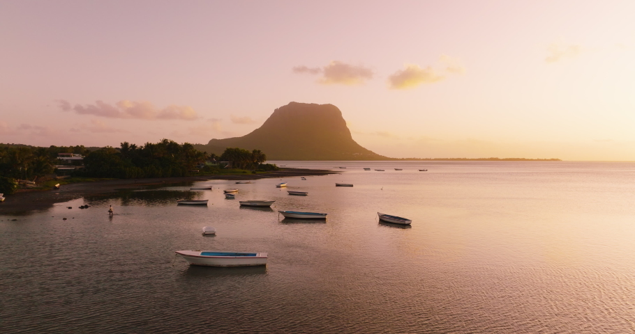 Paradise rocky tropical island at sunset aerial view. Boats on the beach and Le Morne Brabant UNESCO World Heritage Site at sunset time. Mauritius Royalty-Free Stock Footage #1089379421
